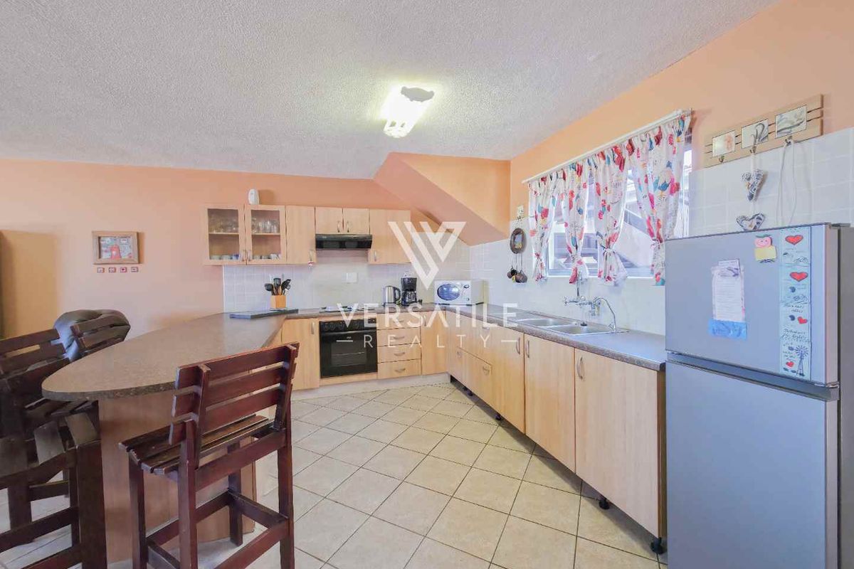 A functional kitchen featuring light wood-finish cabinetry, laminate countertops, a double-basin sink, and an integrated breakfast bar area.