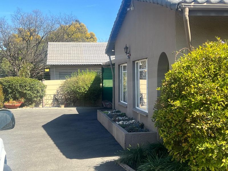 Side view of the property exterior featuring a concrete driveway, built-in planter box, and tiled roof structure.