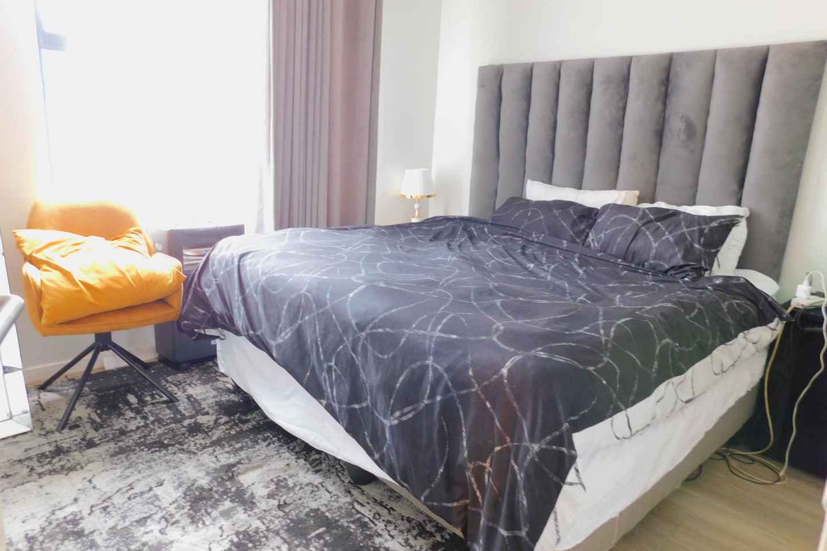 A well-lit bedroom featuring laminate flooring and a large window with curtain tracks, providing a comfortable and functional living space.