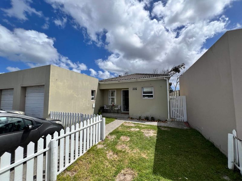 Front exterior view of a townhouse featuring a paved walkway, small lawn area, picket fencing, and an attached garage.