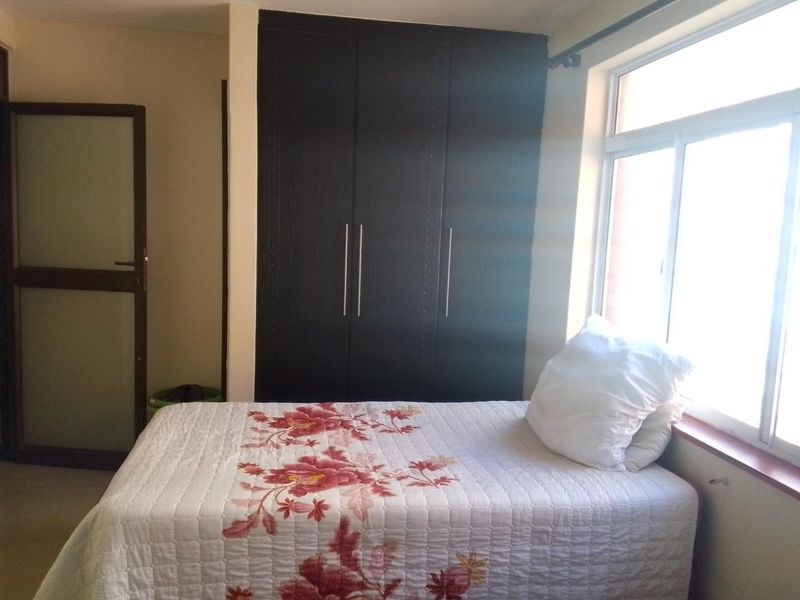 A bedroom featuring a dark built-in wardrobe and a large window providing natural light.