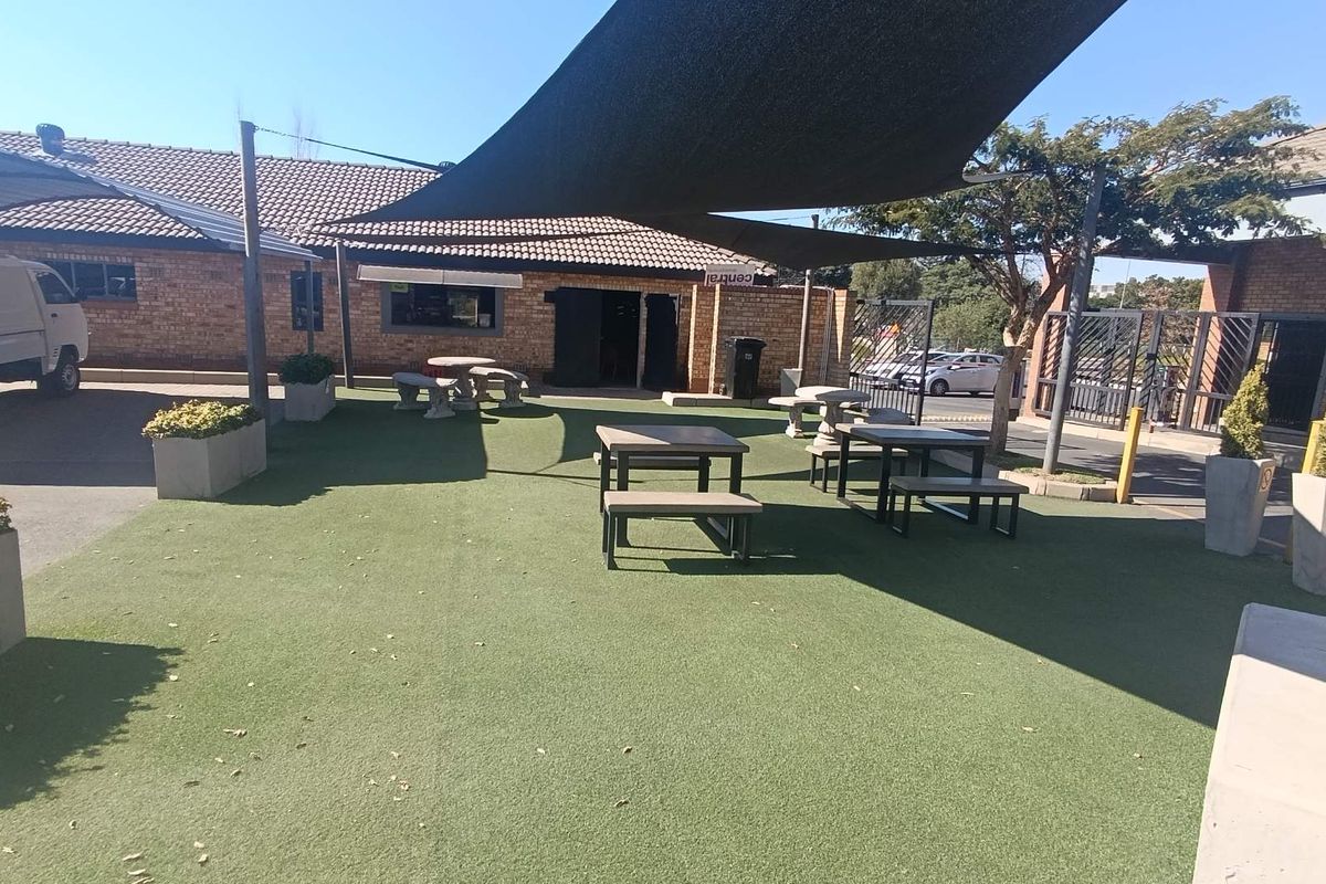 Outdoor courtyard area featuring artificial turf, shade sails, and concrete planters, providing a functional communal space for residents.