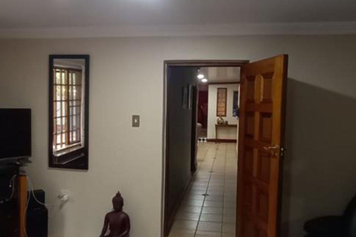 A view from a bedroom looking through a wooden door into a tiled hallway.
