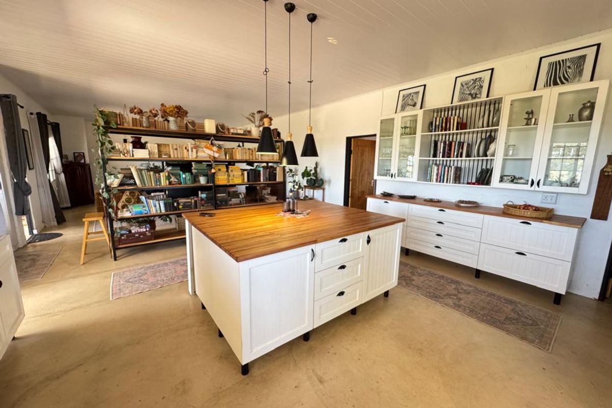 Spacious kitchen featuring a large central island with a timber countertop, extensive built-in cabinetry, and elegant pendant lighting in a bright, open-plan setting.