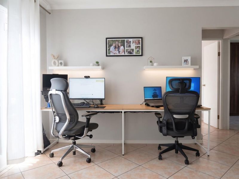 A functional home office space featuring tiled flooring and dual floating shelves, providing a clean and organized workspace.