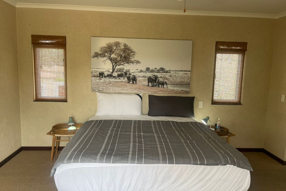 A bedroom featuring textured walls, a ceiling fan, and dual windows with bamboo blinds, providing a neutral foundation for interior updates.