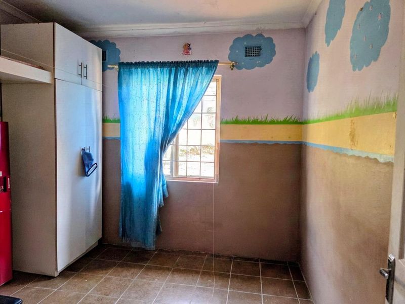 A bedroom featuring tiled flooring, a built-in wardrobe, and a window with security bars, currently finished with decorative wall murals.