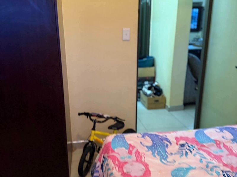 A bedroom featuring tiled flooring and a built-in wardrobe, with a doorway leading to an adjacent living area.