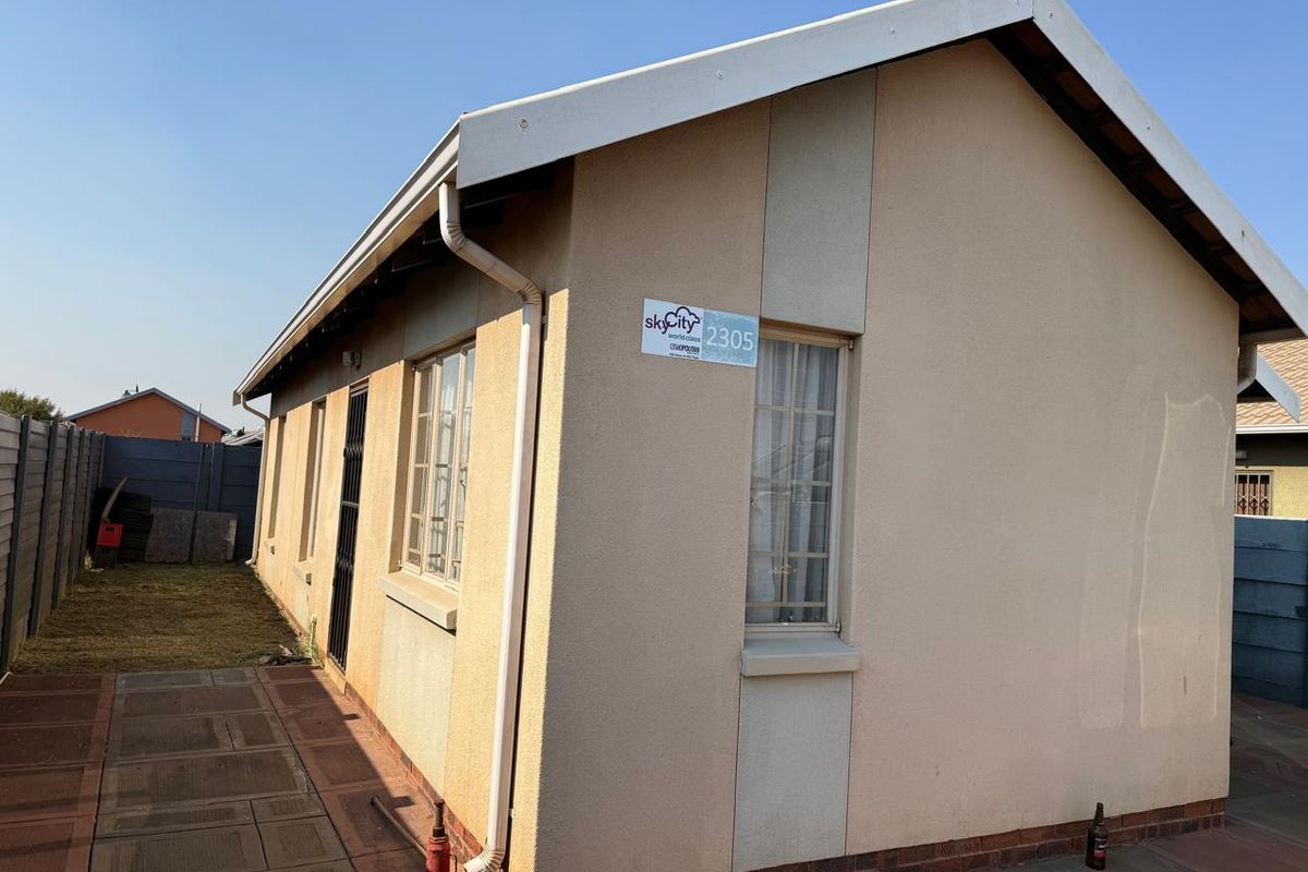 Rear exterior view of the property featuring a plastered facade, tiled roof, paved walkway, and secure window bars.