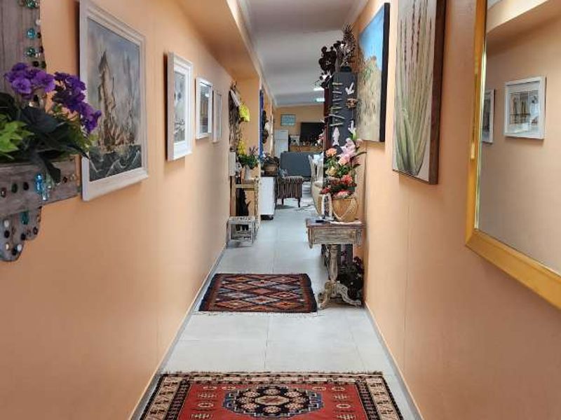 A long, bright hallway featuring tiled flooring and a skylight, providing a clear transition between the living areas of the home.