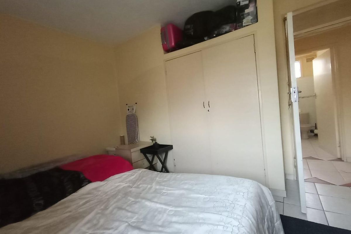 A bedroom featuring a built-in wardrobe with overhead storage and direct access to an adjoining bathroom.