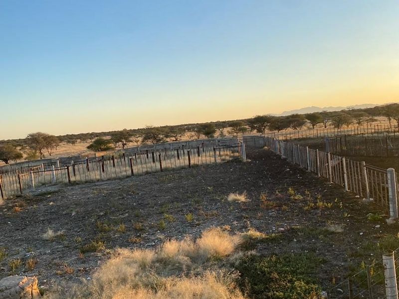 An expansive outdoor farm area featuring wire fencing with concrete posts, set against a natural landscape.