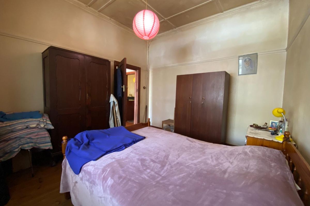 A bedroom featuring original timber flooring, high ceilings with period detailing, and traditional door frames.
