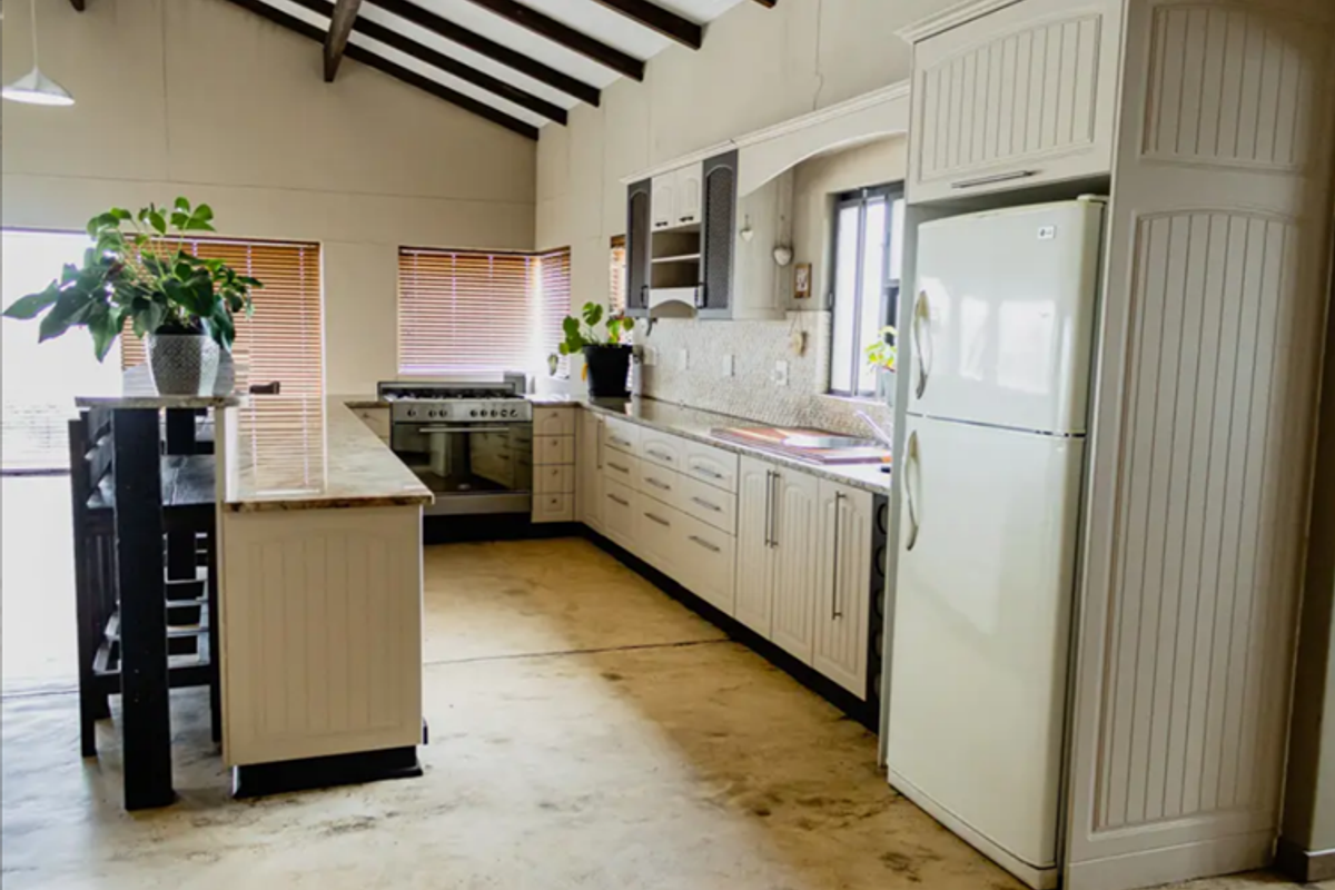 Spacious kitchen featuring a breakfast bar, built-in cabinetry, granite countertops, and exposed timber ceiling beams, offering a functional layout with ample storage.