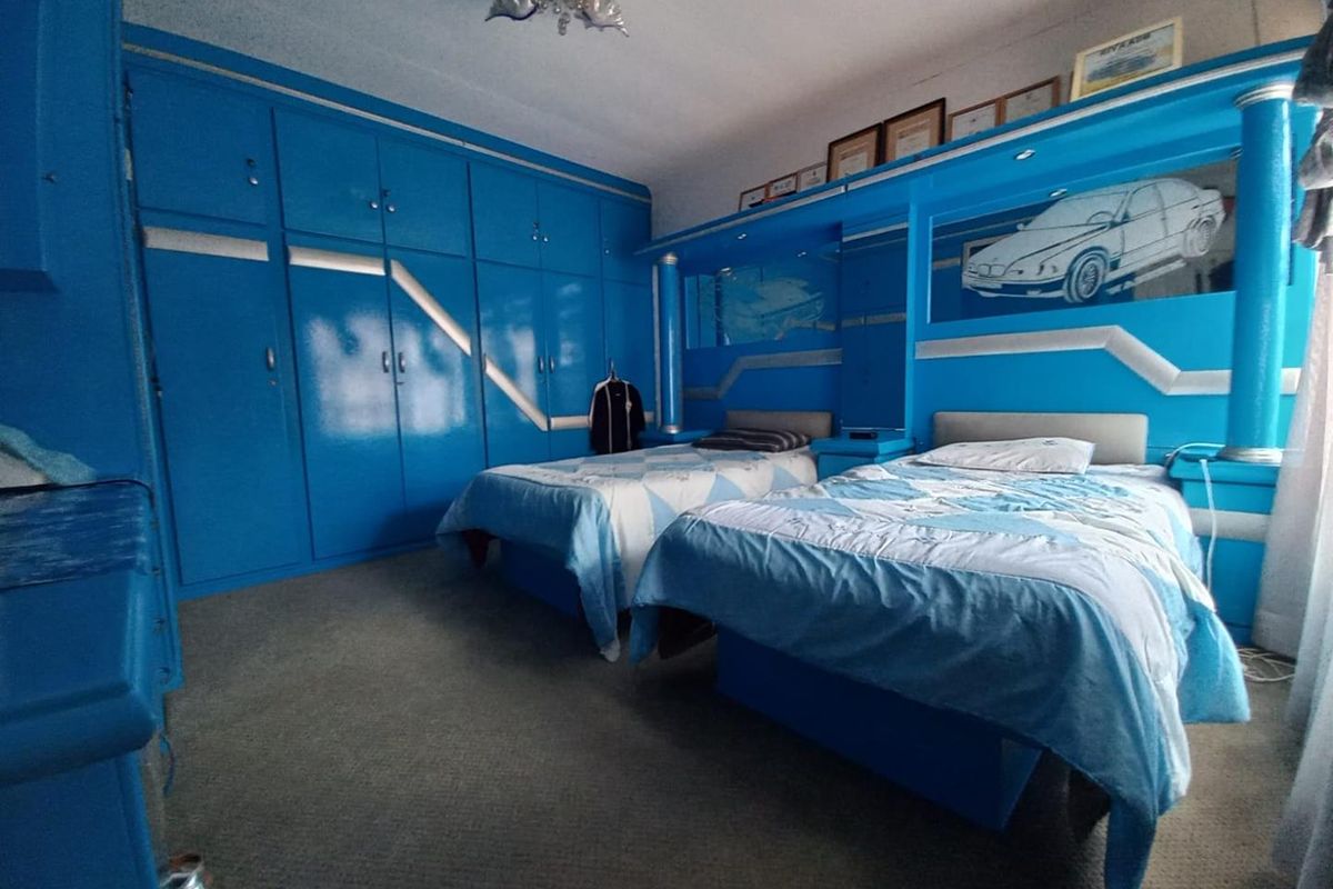 A bedroom featuring extensive built-in blue cabinetry and integrated headboard storage units, offering significant storage space within a dated interior design.