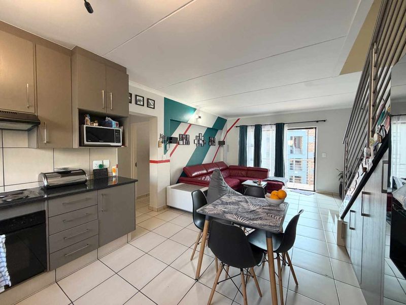 Open-plan living area featuring a modern kitchen with built-in cabinetry, tiled flooring, and direct access to a balcony via a sliding door.