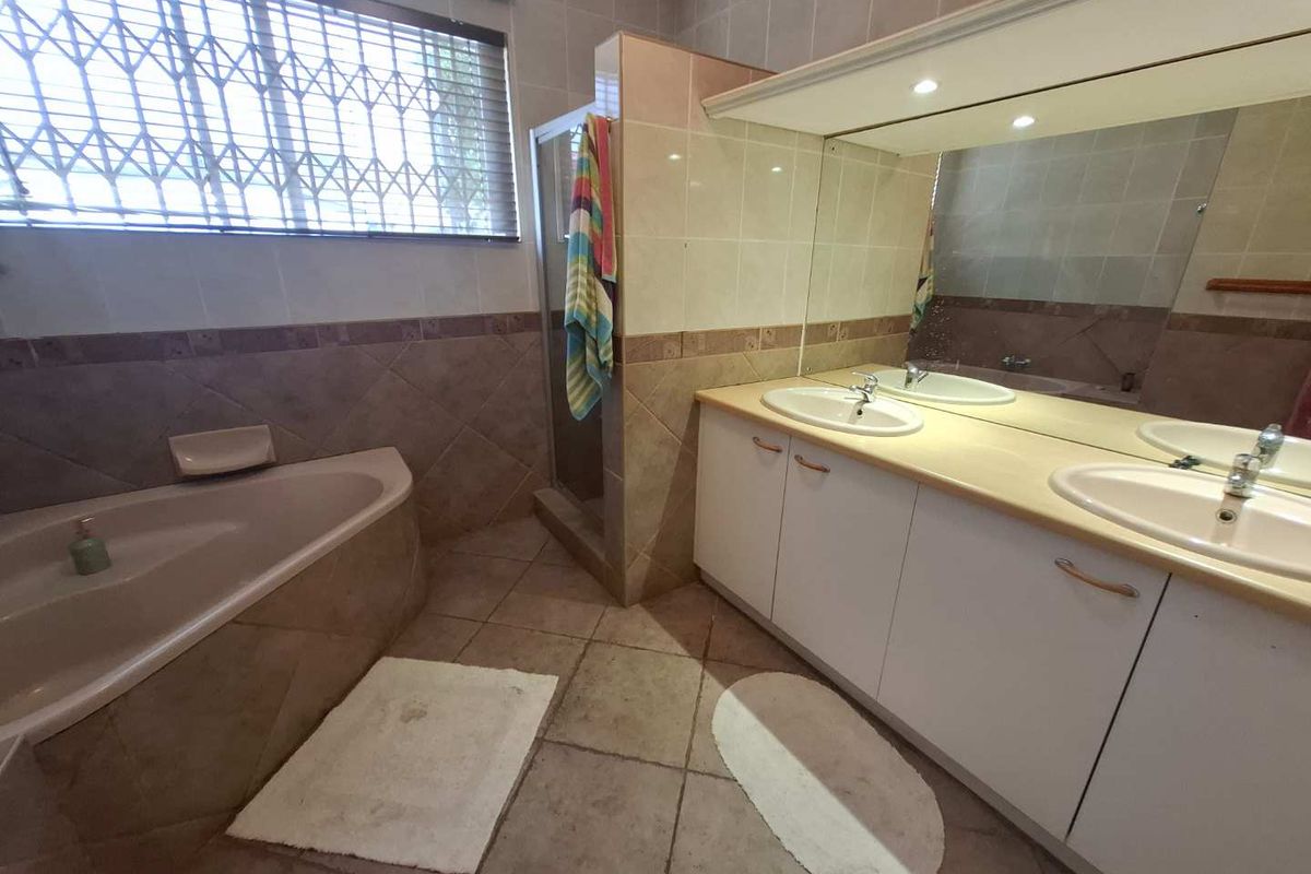 A functional bathroom featuring a corner bathtub, a separate shower enclosure, and a double vanity with integrated sinks and a large wall mirror.