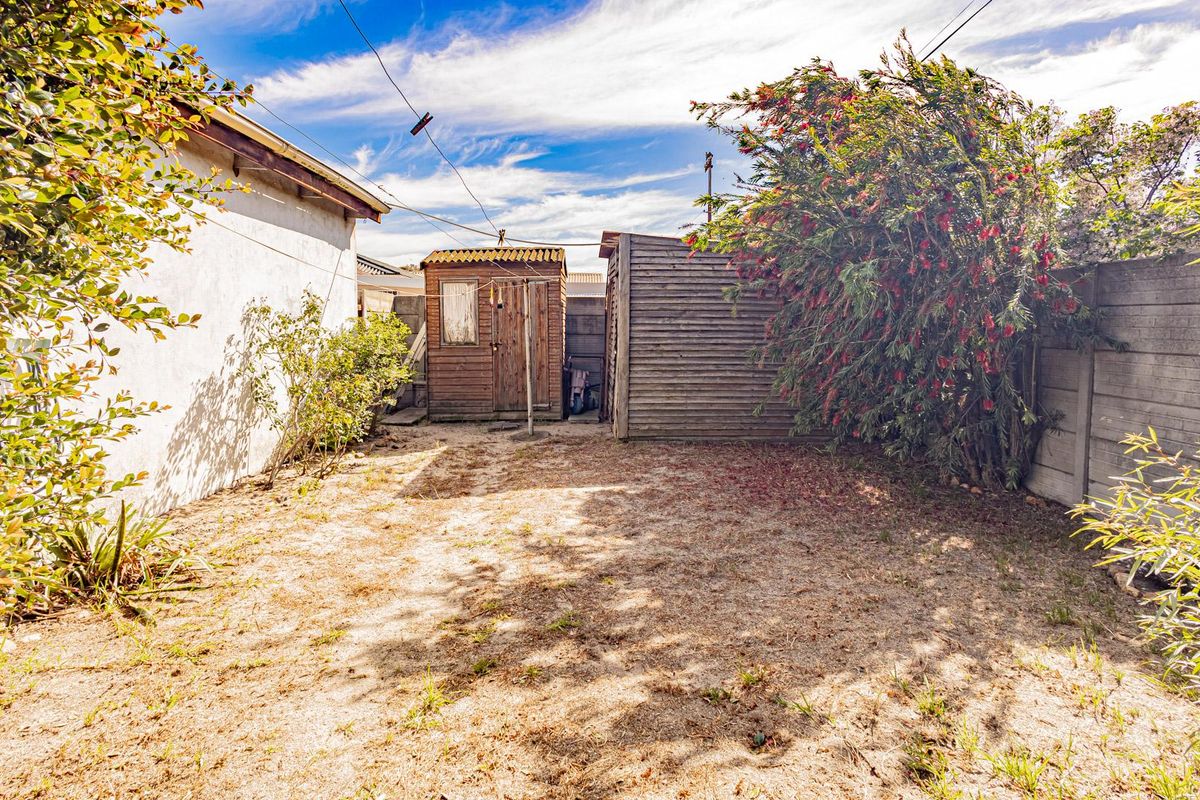 Rear garden area featuring a timber shed, concrete boundary wall, and established landscaping, offering potential for outdoor improvement and garden development.