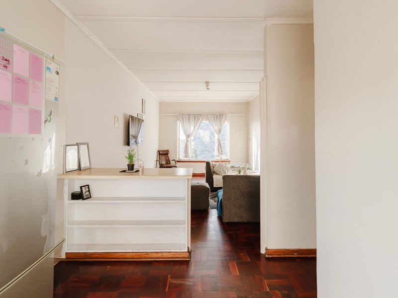 Open plan living area featuring traditional parquet flooring and a built-in shelving unit, providing a functional layout with natural light.