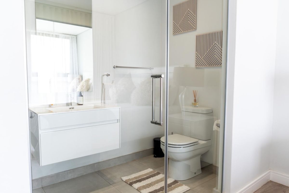 Modern bathroom featuring a wall-mounted vanity with integrated basin, a glass-enclosed shower, and a contemporary toilet.