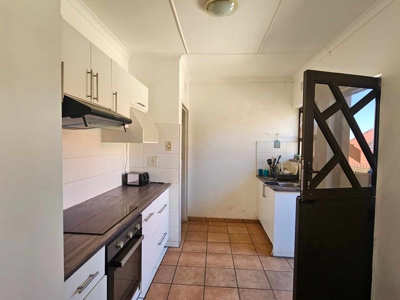Functional kitchen featuring built-in cabinetry, laminate countertops, electric hob, oven, extractor fan, and tiled flooring with direct access via a stable door.