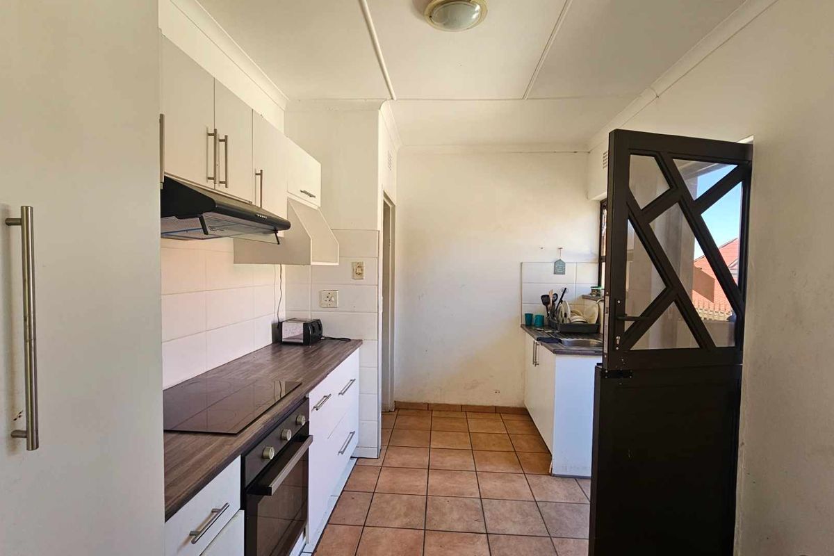 Functional kitchen featuring built-in cabinetry, laminate countertops, electric hob, oven, extractor fan, and tiled flooring with direct access via a stable door.
