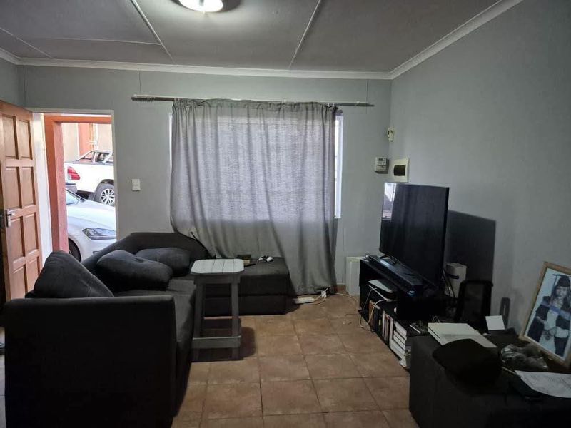 A functional living room featuring tiled flooring and neutral wall finishes, providing a comfortable space for relaxation.