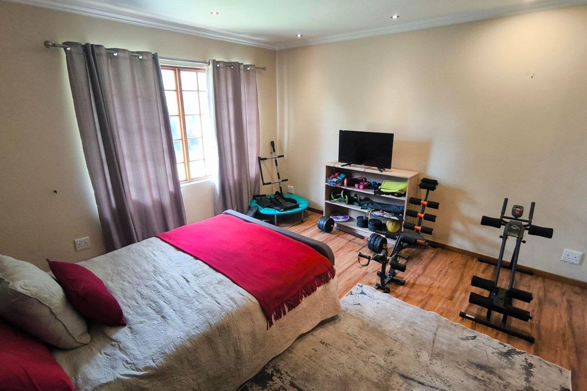 A bedroom featuring laminate wood flooring, recessed ceiling lighting, and a window with curtain rods.