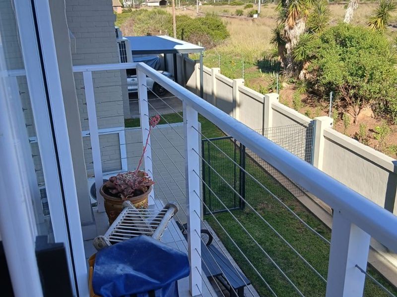 A private balcony featuring a white metal balustrade with cable railing, overlooking the garden and surrounding landscape.