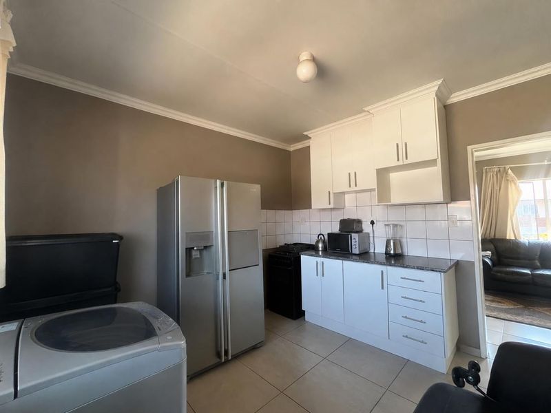 A functional kitchen featuring white cabinetry, tiled backsplash, and tiled flooring, offering a clean and practical layout for daily meal preparation.