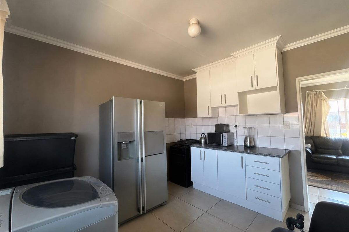 A functional kitchen featuring white cabinetry, tiled backsplash, and tiled flooring, offering a clean and practical layout for daily meal preparation.