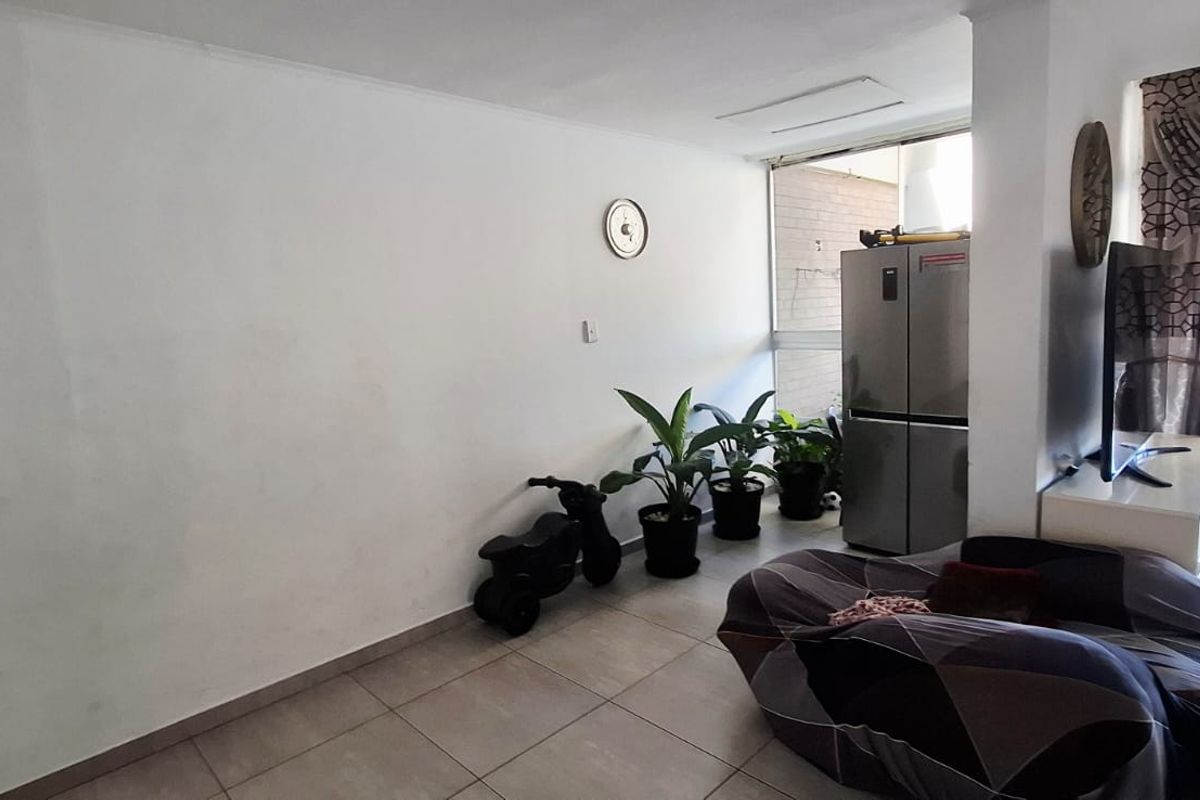 A living area featuring tiled flooring and a large sliding glass door providing access to an outdoor space.