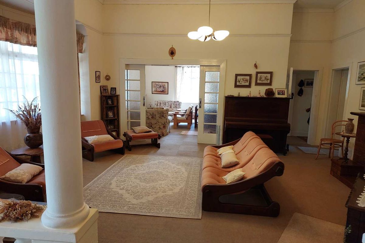 Spacious living area featuring classic architectural details, including a prominent column and glass-paneled sliding doors connecting to an adjacent room.