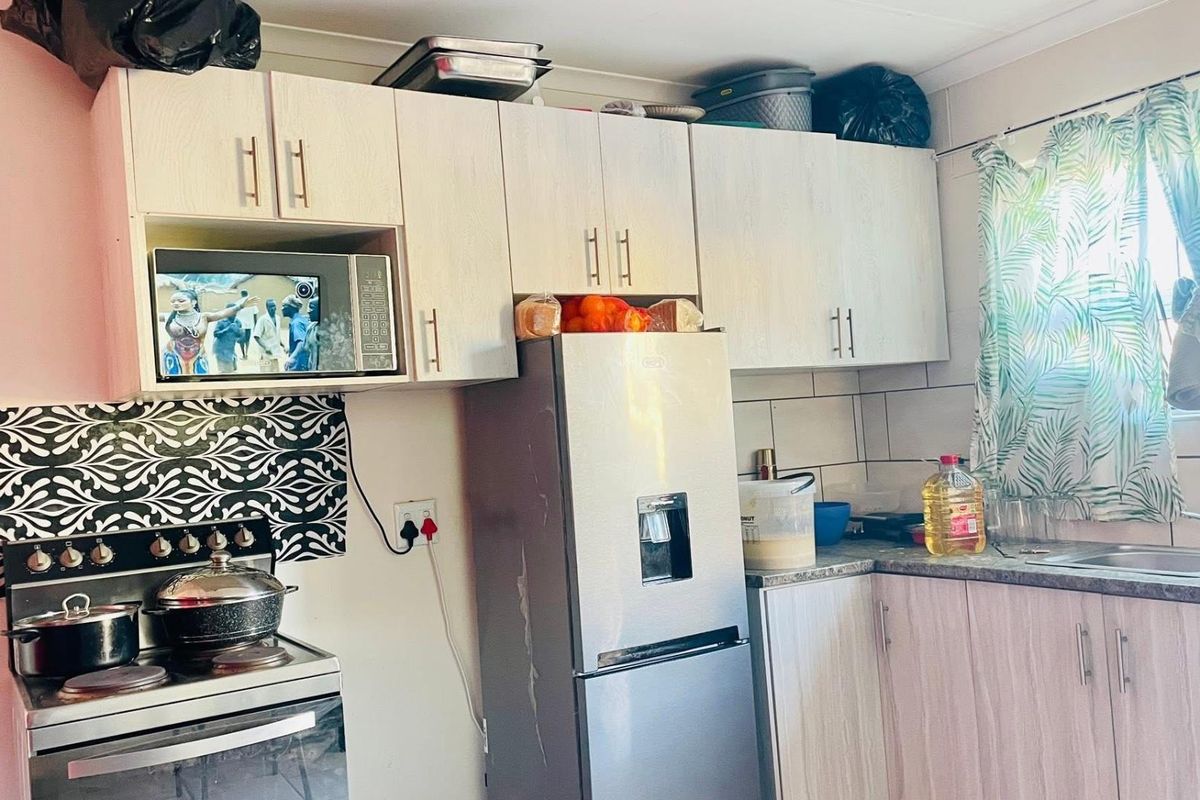A functional kitchen featuring light wood-grain cabinetry, tiled backsplash, stainless steel sink, and built-in microwave space.