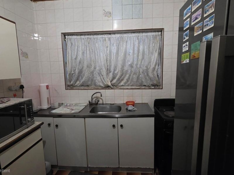 A compact kitchen featuring basic cabinetry, a stainless steel sink, and tiled backsplash, requiring modernization to improve functionality and aesthetic appeal.