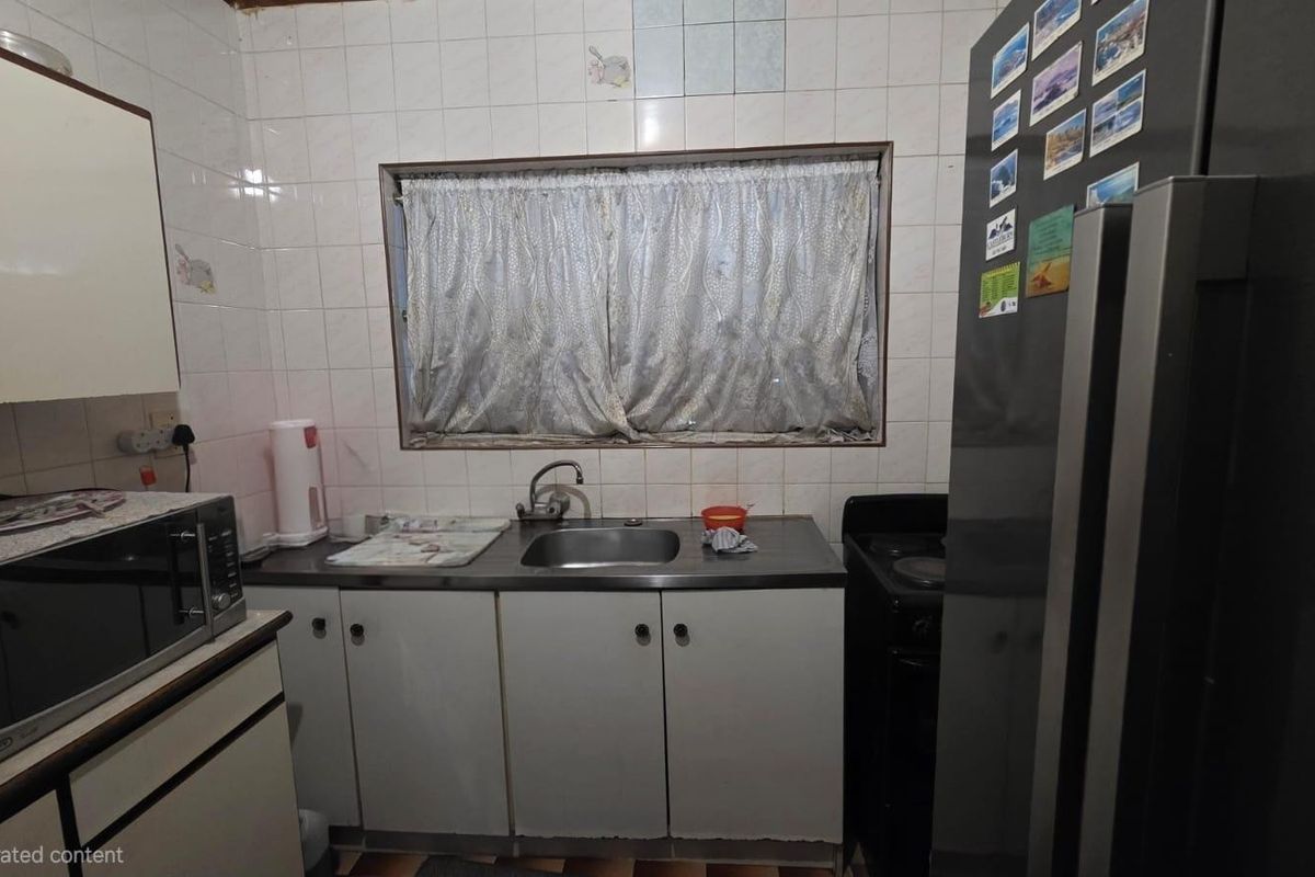 A compact kitchen featuring basic cabinetry, a stainless steel sink, and tiled backsplash, requiring modernization to improve functionality and aesthetic appeal.