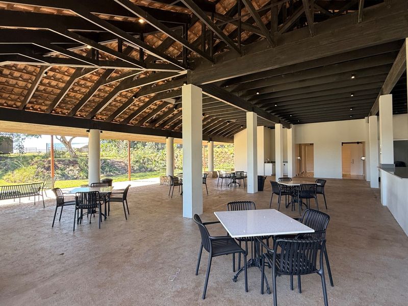 A spacious covered outdoor patio area featuring exposed timber roof trusses, concrete columns, and recessed lighting, ideal for large gatherings or events.