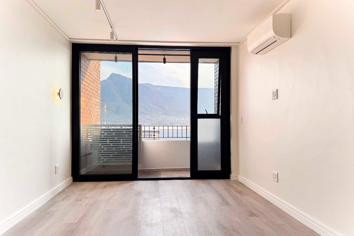 Bright and modern living area featuring laminate flooring, split-system air conditioning, and large sliding glass doors opening to a balcony with mountain views.