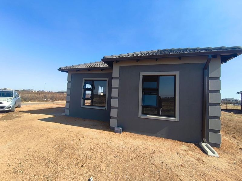 A modern single-story house exterior featuring dark grey painted walls with contrasting quoins, tiled roof, and aluminium window frames.