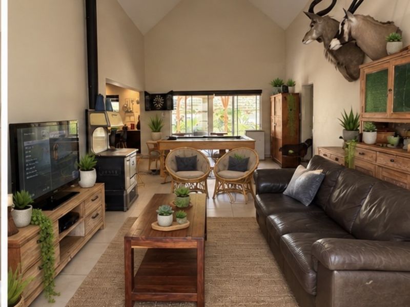 Spacious open-plan living area featuring a high vaulted ceiling, tiled flooring, and a prominent freestanding fireplace, with direct access to the outdoor space.