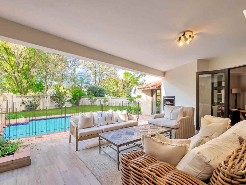 A spacious covered patio overlooking a private swimming pool and garden, featuring tiled flooring and direct access to the main living area.