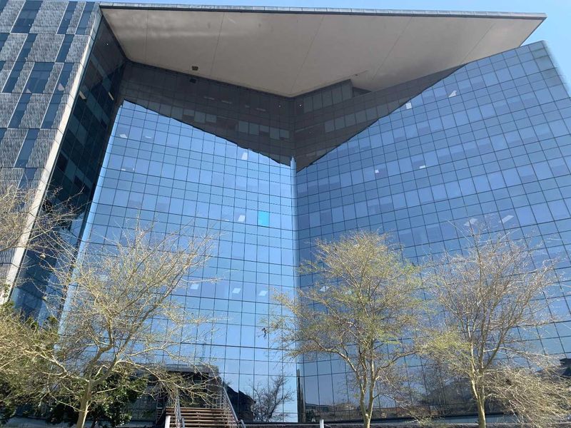 Modern commercial office building featuring a striking glass curtain wall facade and a prominent overhanging roof structure.