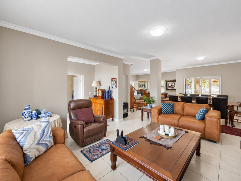 Spacious open-plan living and dining area featuring neutral wall tones, tiled flooring, and classic cove cornicing, providing a comfortable and well-lit family space.