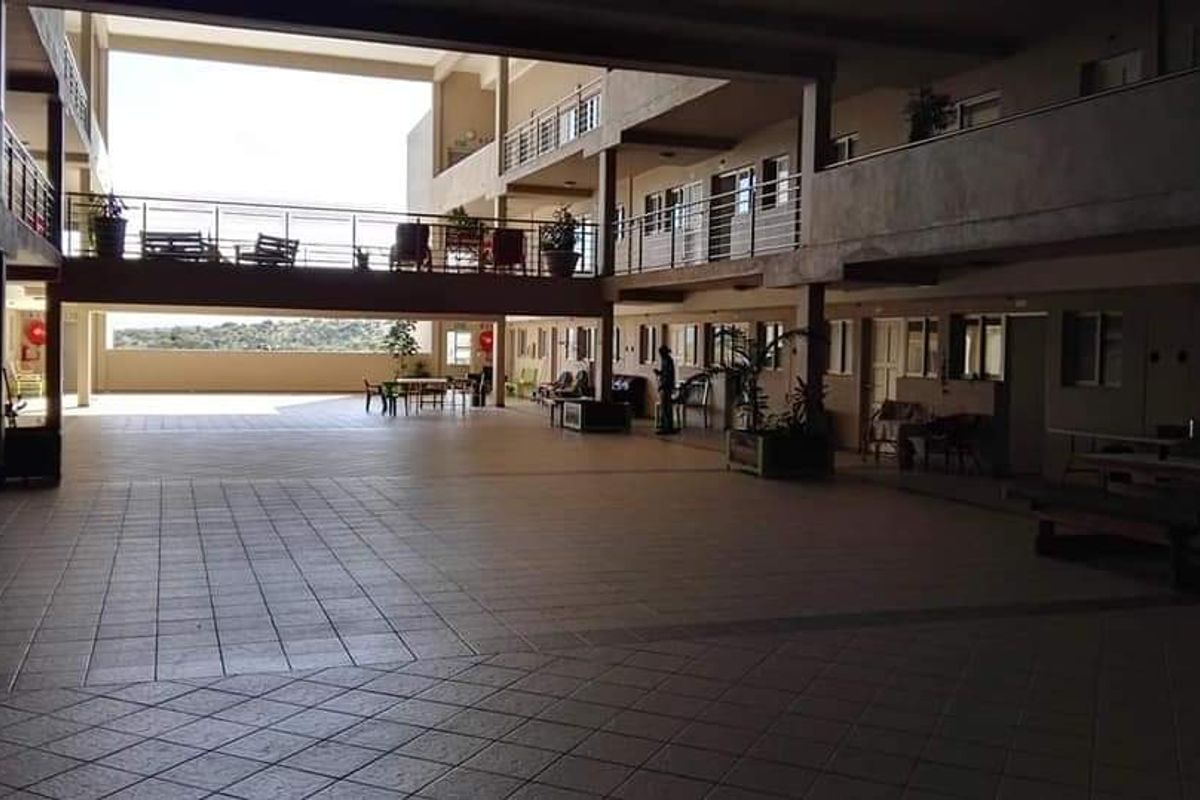 A spacious open-air communal courtyard area within an apartment complex, featuring tiled flooring and multi-level balcony walkways.