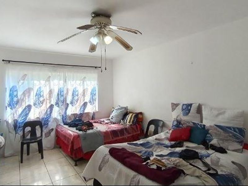 A bedroom featuring tiled flooring and a ceiling fan, providing a functional space with natural light.