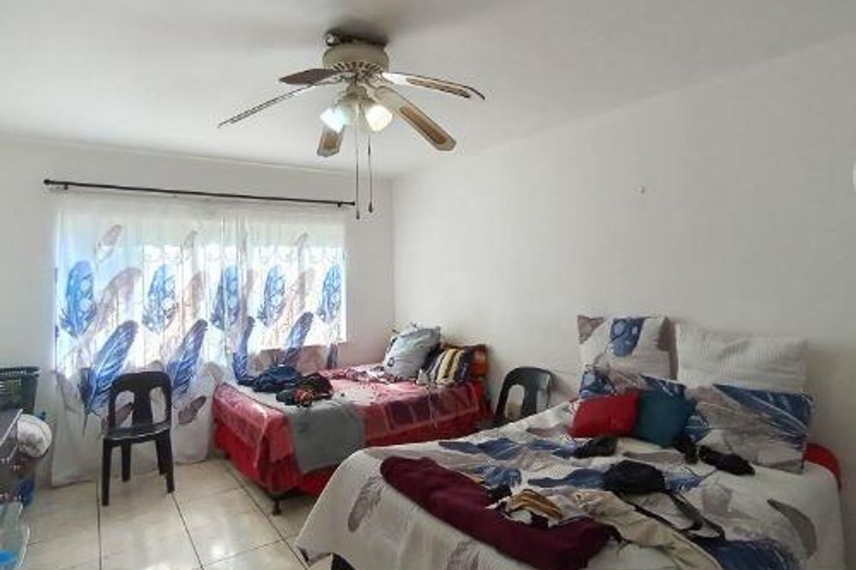 A bedroom featuring tiled flooring and a ceiling fan, providing a functional space with natural light.