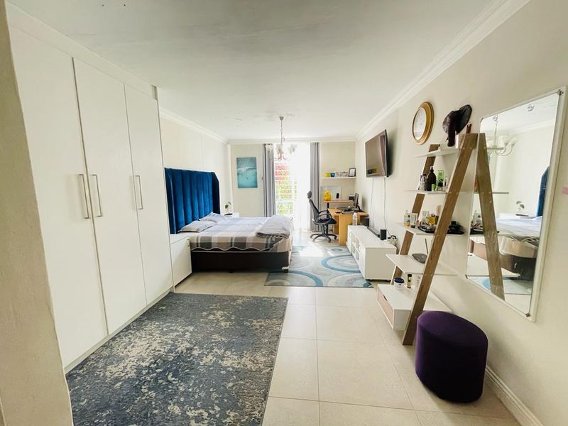 Spacious bedroom featuring large built-in wardrobes, tiled flooring, and access to a balcony through a sliding door.