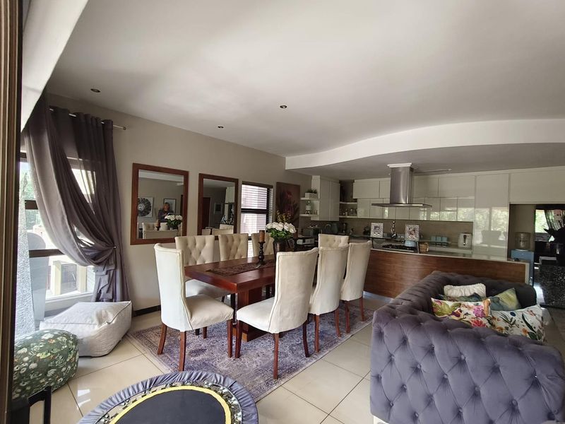 Spacious open-plan living and dining area featuring modern tiled floors, recessed lighting, and a contemporary kitchen with integrated cabinetry and stainless steel extractor.
