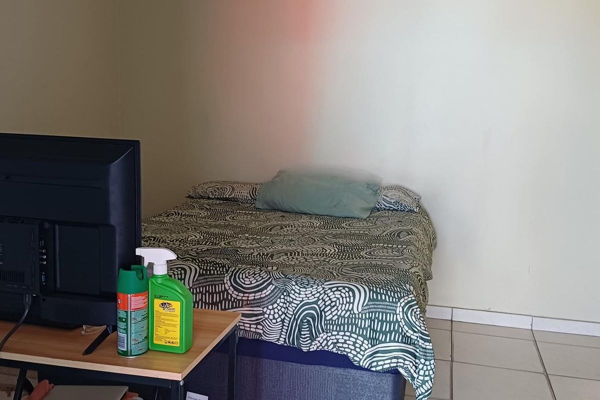 A bedroom featuring tiled flooring and a standard door, providing a functional living space.