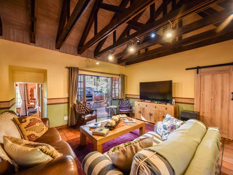 Spacious living room featuring a vaulted ceiling with exposed timber trusses, terracotta flooring, and direct access to an outdoor patio area.